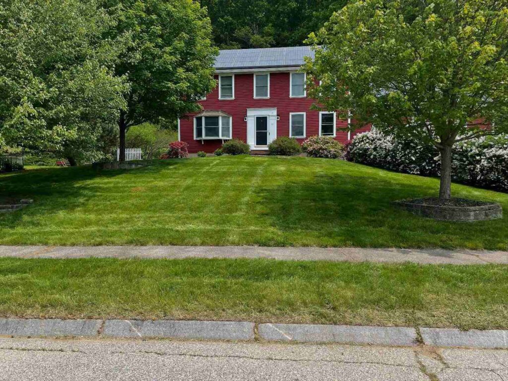 Red home with a freshly mowed front yard and clean sidewalk edge in Essex.